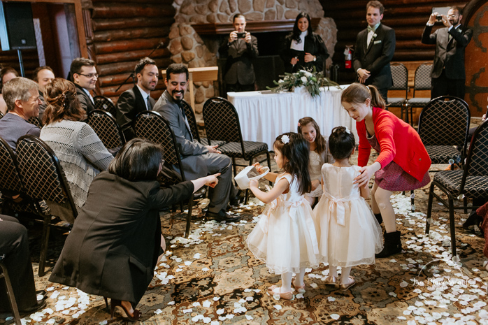 Winter wedding photos in the snow. Indoor ceremony in wooden cabin by the fire place wooden walls harsh light natural light. Flower girls and bridesmaids walking down the aisle. Mariage féerique hivernal à l'Hôtel Mont-Gabriel. Mariage hiver Laurentides. Photographe mariage Montréal | Lisa-Marie Savard Photographie | Montréal, Québec | www.lisamariesavard.com
