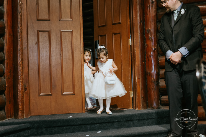 Winter wedding photos in the snow. Indoor ceremony in wooden cabin by the fire place wooden walls harsh light natural light. Flower girls and bridesmaids walking down the aisle. Mariage féerique hivernal à l'Hôtel Mont-Gabriel. Mariage hiver Laurentides. Photographe mariage Montréal | Lisa-Marie Savard Photographie | Montréal, Québec | www.lisamariesavard.com