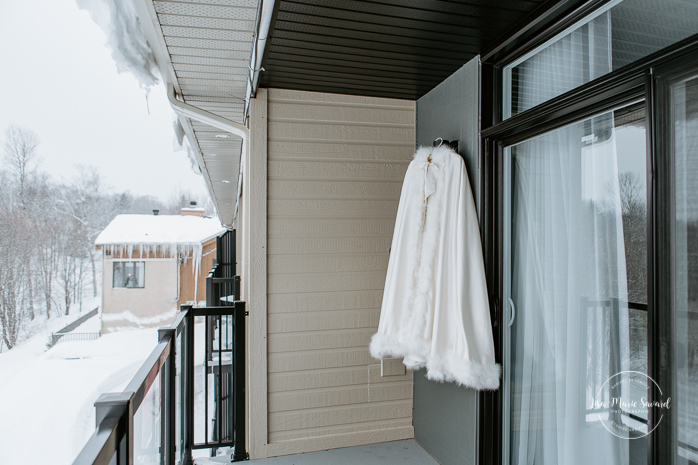 Winter wedding photos in the snow. Bride getting ready with mom sister friend bridesmaids. Bridal details wedding dress hanging outside in the snow cape hanging outside in the snow. Mariage féerique hivernal à l'Hôtel Mont-Gabriel. Mariage hiver Laurentides. Photographe mariage Montréal | Lisa-Marie Savard Photographie | Montréal, Québec | www.lisamariesavard.com