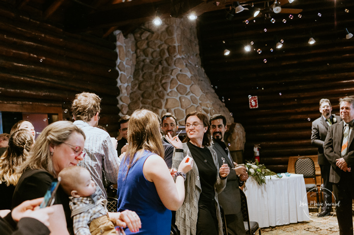 Winter wedding photos in the snow. Indoor ceremony in wooden cabin by the fire place wooden walls harsh light natural light. Guests reactions during the ceremony smiling laughing crying. Mariage féerique hivernal à l'Hôtel Mont-Gabriel. Mariage hiver Laurentides. Photographe mariage Montréal | Lisa-Marie Savard Photographie | Montréal, Québec | www.lisamariesavard.com