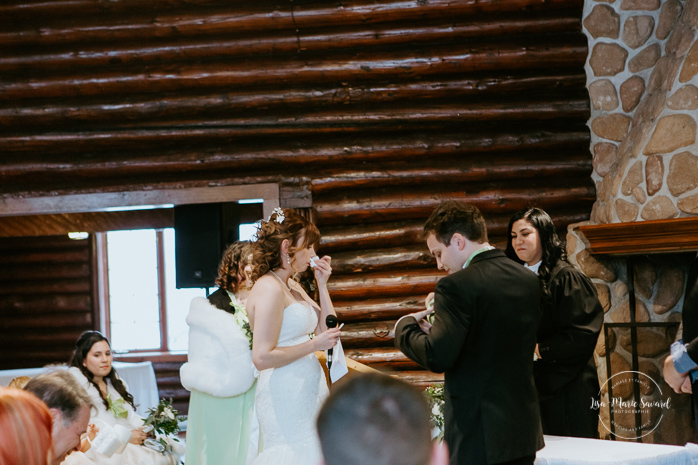 Winter wedding photos in the snow. Indoor ceremony in wooden cabin by the fire place wooden walls harsh light natural light. Bride and groom exchanging vows during ceremony. Mariage féerique hivernal à l'Hôtel Mont-Gabriel. Mariage hiver Laurentides. Photographe mariage Montréal | Lisa-Marie Savard Photographie | Montréal, Québec | www.lisamariesavard.com