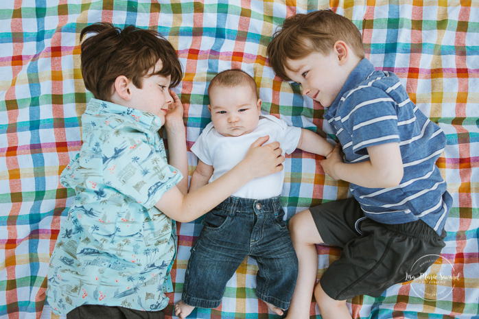 Big brothers laying next to baby brother on a blanket. Outdoor family photos. Photographe de famille à Verdun. Verdun family photographer.