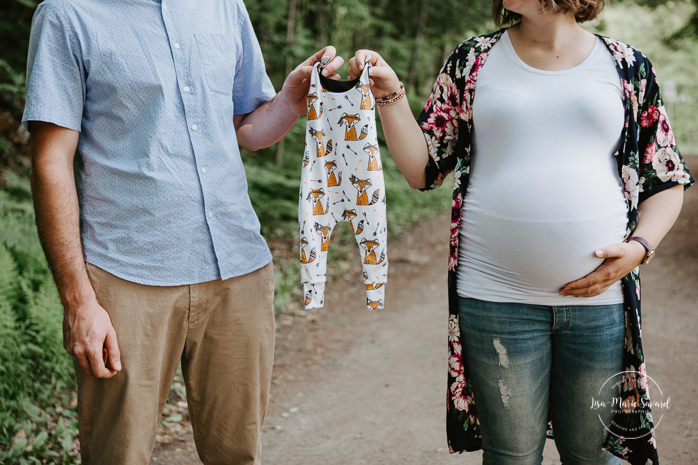 Forest maternity photos. Onesie maternity photos. Parents holding onesie pregnancy announcement. Photographe de grossesse sur la Rive-Nord. Parc régional de la Rivière du Nord. Montreal maternity photographer