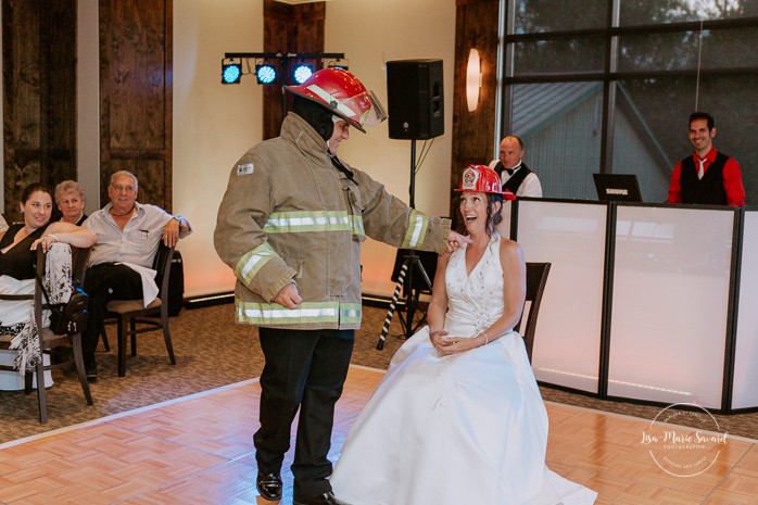 Firefighter groom doing a funny striptease to his wife. Mariage à Sainte-Agathe-des-Monts. Mariage an golf de Val-Morin. Photographe de mariage dans les Laurentides. Laurentians wedding photographer.