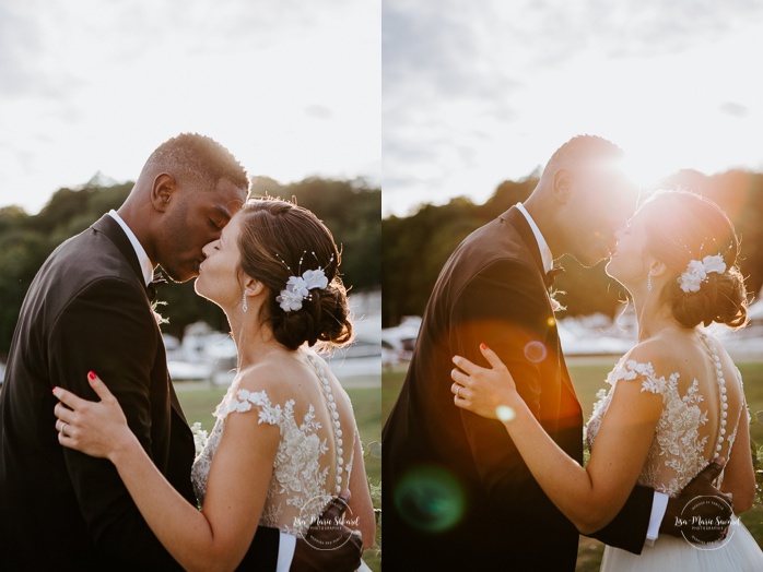 Bride and groom kissing in front of sunset flare. African American groom and Caucasian bride. Mariage en Outaouais. Fairmont Le Château Montebello outdoor wedding. Ottawa photographer.