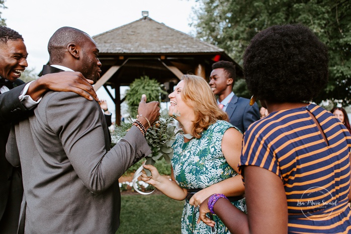 Outdoor bouquet toss during cocktail. African American groom and Caucasian bride. Mariage en Outaouais. Fairmont Le Château Montebello outdoor wedding. Ottawa photographer.