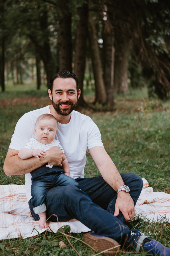 Dad holding smiling baby boy. Outdoor family photos with three months old baby boy. Three months milestones. Family photos at the park. Photographe de famille à Montréal.