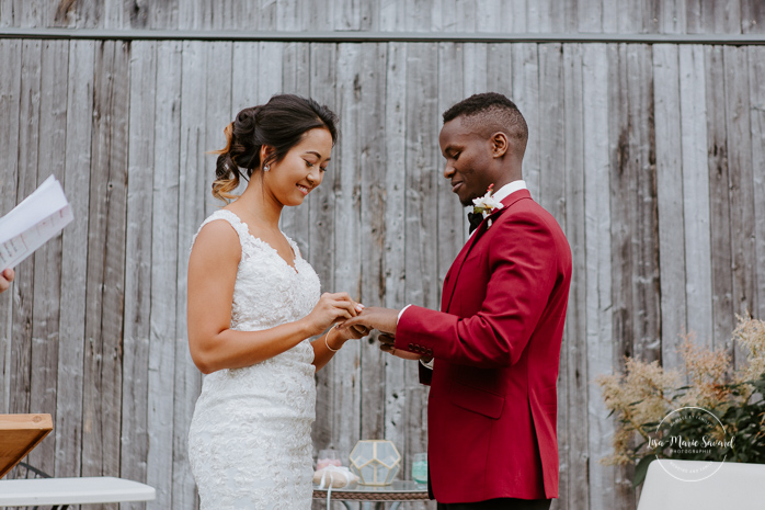 Fall barn wedding. Fall outdoor wedding ceremony. Bride and groom exchanging rings. Mixed wedding with Asian bride and Black groom. Mariage à l'Orée des Champs en automne. Orée des Champs Saint-Nazaire Saguenay-Lac-Saint-Jean. Photographe de mariage Saguenay