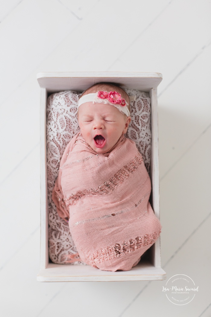 Newborn girl yawning. Minimalist girl newborn session. White wooden bed. Newborn photos pink. Organic floral headband newborn. Photos de nouveau-né à Verdun. Verdun newborn photographer.