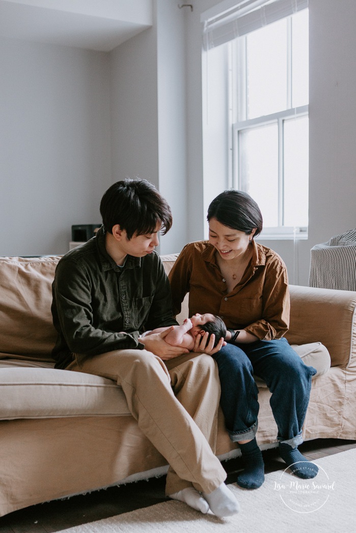 Intimate in-home newborn session. Lifestyle newborn photos. Parents and baby sitting on couch. Photoshoot de bébé à Montréal. Old Montreal newborn photographer. Montreal travel photographer.