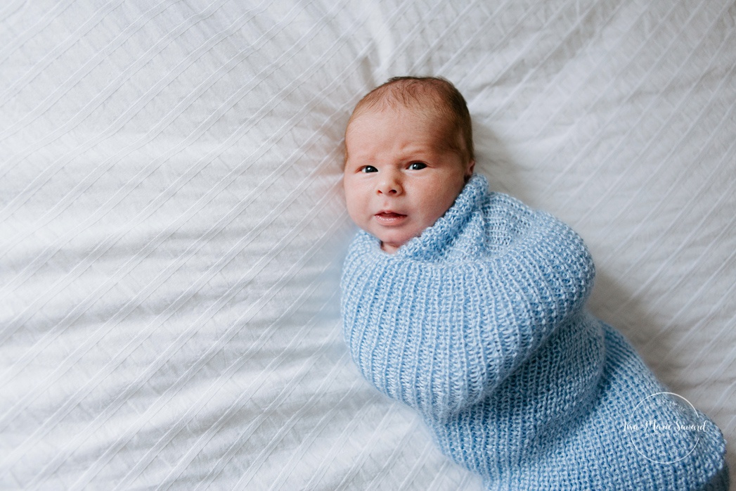 In-home lifestyle newborn session. Newborn photos in nursery. Baby boy wrapped in blanket on bed. Photos de bébé à Montréal. Montreal North Shore newborn photoshoot.