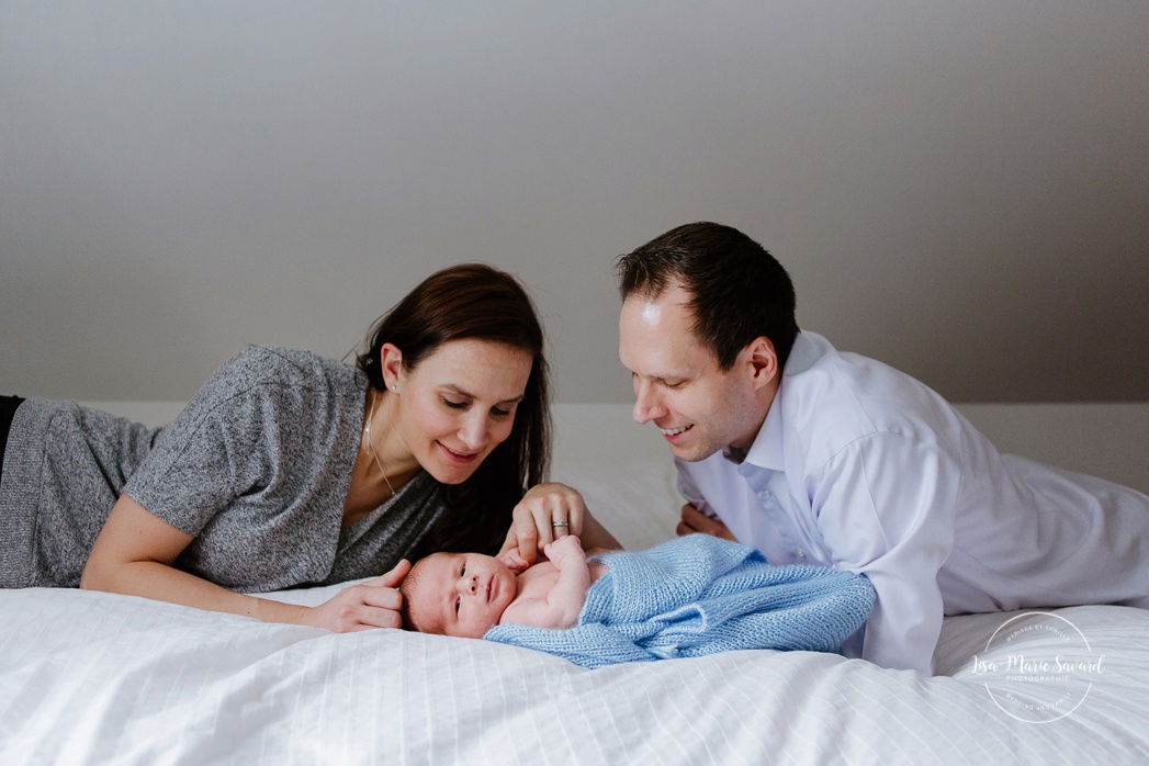In-home lifestyle newborn session. Newborn photos on bed. Mom and dad laying with baby on bed. Séance nouveau-né sur la Rive-Nord de Montréal. Montreal North Shore newborn photoshoot.