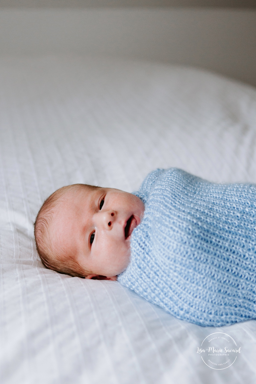 In-home lifestyle newborn session. Newborn photos in nursery. Baby boy wrapped in blanket on bed. Photos de bébé à Montréal. Montreal North Shore newborn photoshoot.