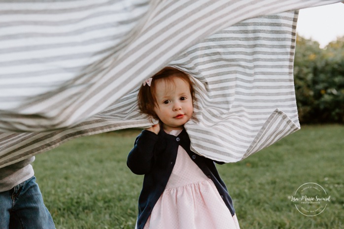 Children running under blanket. Little girl playing with blanket. Outdoor family session. Outdoor family photos. Family of four photos. Family photos with dog. Photos de famille dans les West Island à Montréal. Photographe de famille à Montréal. Montreal West Island family photos. Montreal family photographer.