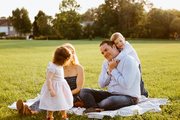 Boy hugging dad from behind. Outdoor family session. Outdoor family photos. Photos de famille dans les West Island à Montréal. Photographe de famille à Montréal. Montreal West Island family photos. Montreal family photographer.