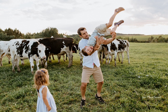 Dad playing fight with little boy. Dairy farm photos with cows. Farm photo session. Family photos with cows. Countryside family photos. Photos de famille à la campagne. Photos de famille dans un champ. Photographe de famille à Montréal. Montreal family photographer.