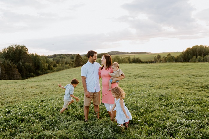 Children running around parents. Dairy farm photos with cows. Farm photo session. Family photos with cows. Countryside family photos. Photos de famille à la campagne. Photos de famille dans un champ. Photographe de famille à Montréal. Montreal family photographer.