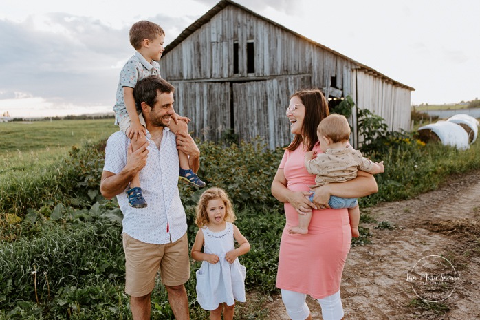 Family photos in front of old barn. Barn family photos. Dairy farm photos with cows. Farm photo session. Family photos with cows. Countryside family photos. Photos de famille à la campagne. Photos de famille dans un champ. Photographe de famille à Montréal. Montreal family photographer.