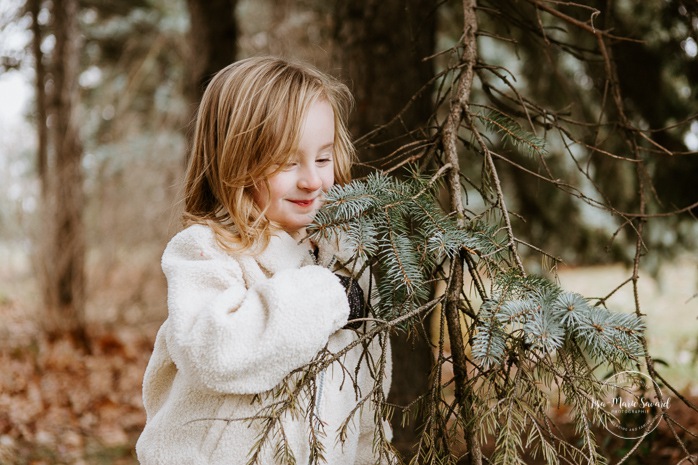 Young girl smelling pine tree. Winter maternity photos without snow. Maternity photos with child. Maternity photos with sibling. Photographe à Ville-Émard. Montreal Southwest maternity photos.