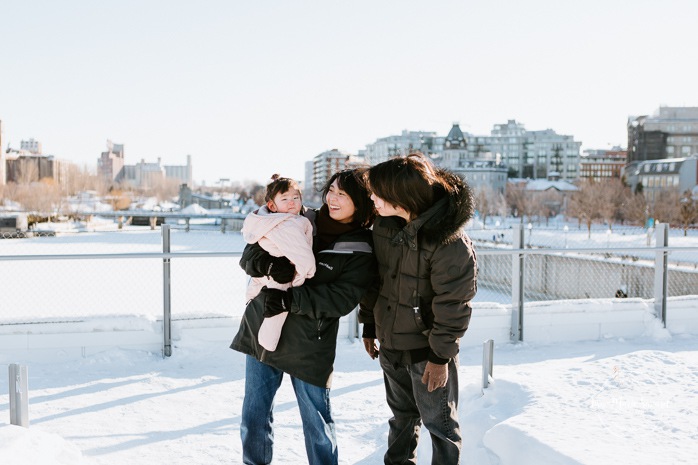 Winter family session. Family photos in the snow. Asian family photos. Family photos cityscape. Skyline family photos. Photos de famille à Montréal. Grand Quai de Montréal. Promenade d'Iberville. Montreal family photos.