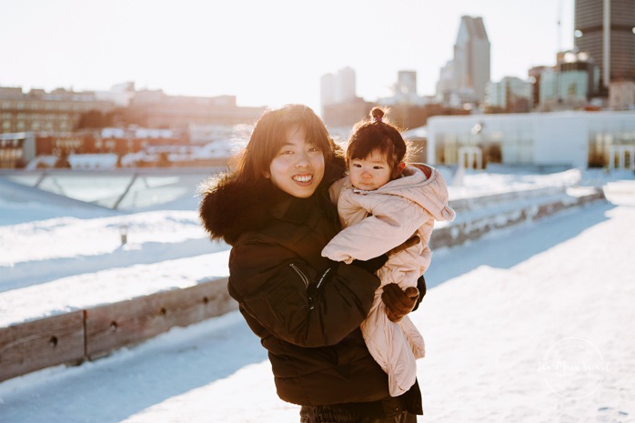 Winter family session. Family photos in the snow. Asian family photos. Family photos cityscape. Skyline family photos. Photos de famille à Montréal. Grand Quai de Montréal. Promenade d'Iberville. Montreal family photos.