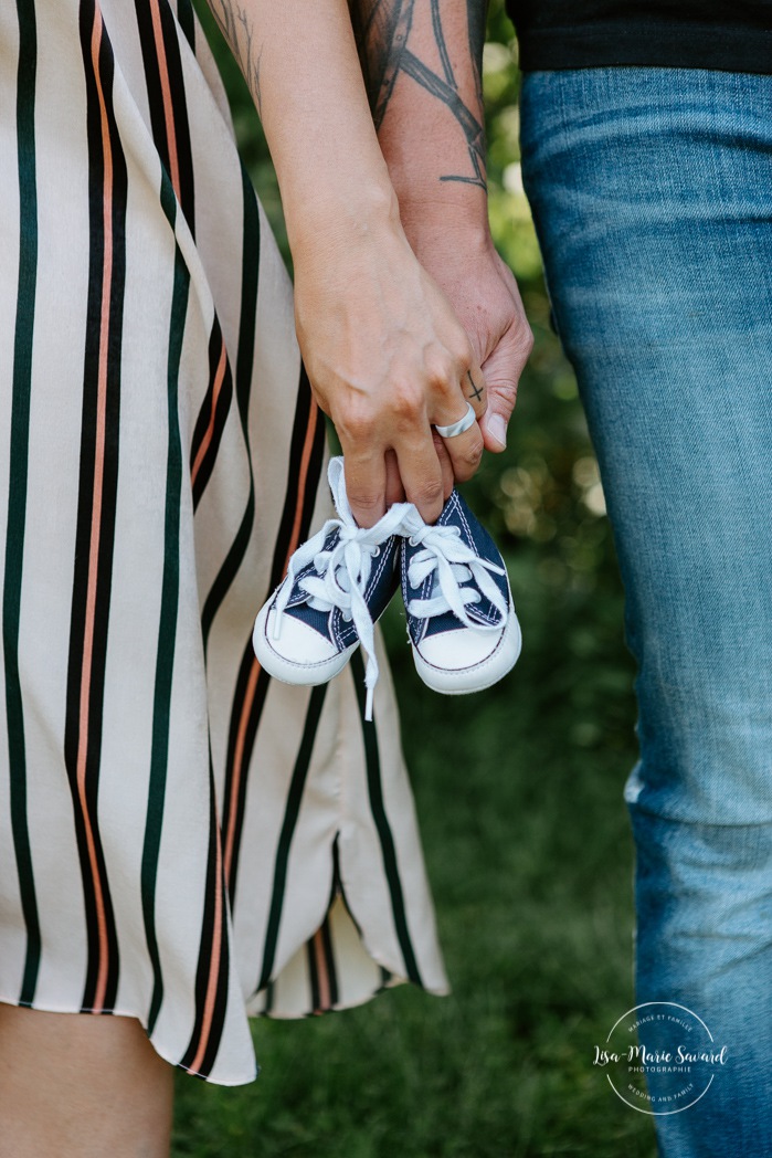 Parents holding baby shoes. Outdoor maternity photos. Lifestyle maternity session. Greenery maternity photos. Forest maternity photos. Photos de maternité au Saguenay. Séance maternité Saguenay. Photographe Saguenay. Saguenay photographer