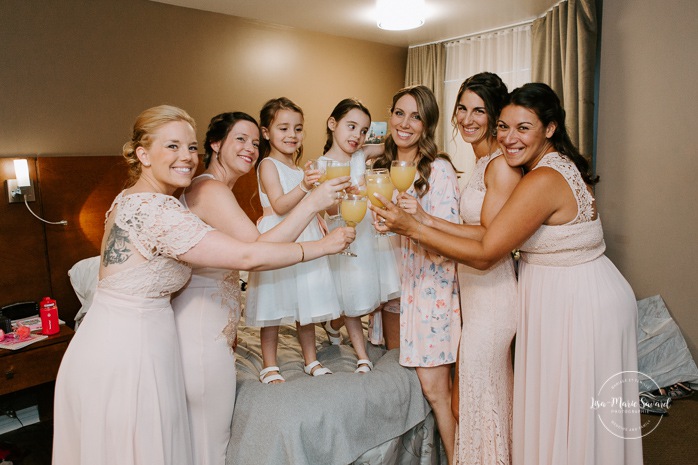 Bride and bridesmaids popping champagne. Bride getting ready with bridesmaids in hotel room. Pandemic wedding. COVID-19 micro wedding. Mariage en Beauce durant la pandémie. Photographe de mariage Beauce. Motel Invitation Sainte-Marie.