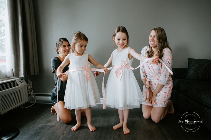 Flower girls putting dresses on. Bride getting ready with bridesmaids in hotel room. Pandemic wedding. COVID-19 micro wedding. Mariage en Beauce durant la pandémie. Photographe de mariage Beauce. Motel Invitation Sainte-Marie.