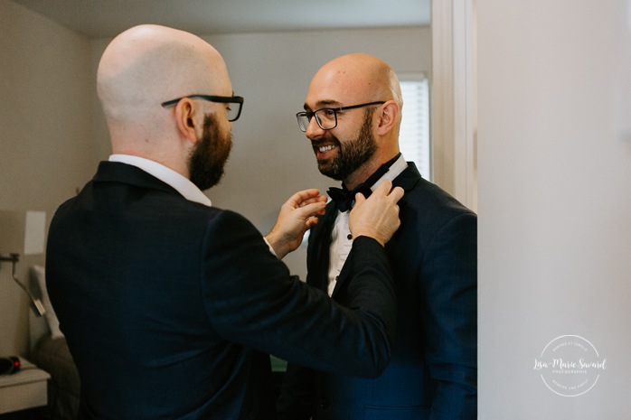 Groom getting ready with groomsmen in hotel room. Mariage en Beauce durant la pandémie. Photographe de mariage Beauce. Motel Invitation Sainte-Marie.