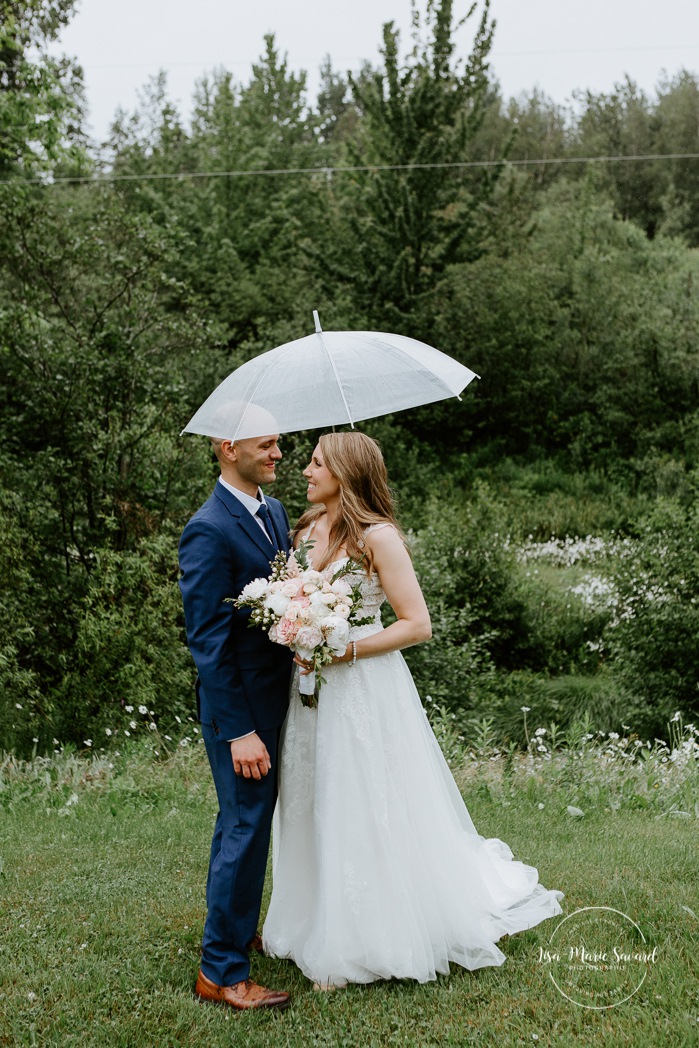 Rainy wedding photos. Wedding photos with clear umbrellas. Mariage en Beauce durant la pandémie. Photographe de mariage Beauce. La Bouche Bée Saint-Sylvestre.