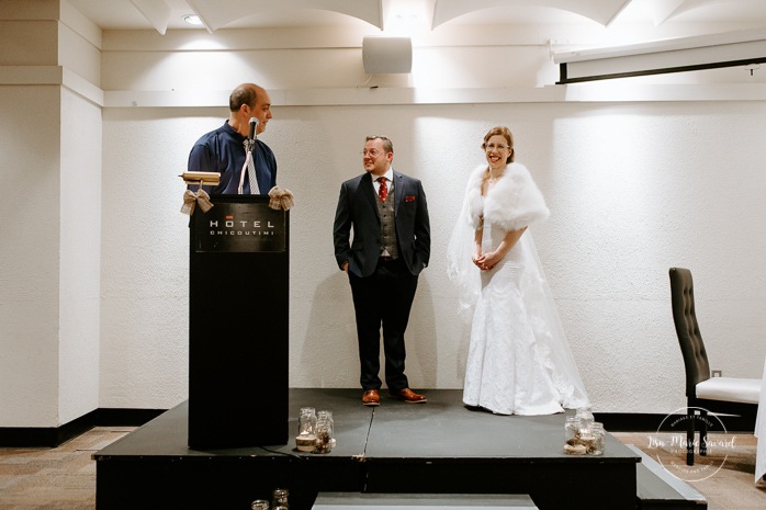 Intimate hotel wedding ceremony. Wedding ceremony in dark hall with artificial light. Mariage à Chicoutimi en hiver. Photographe de mariage au Saguenay. Mariage Hôtel Chicoutimi.