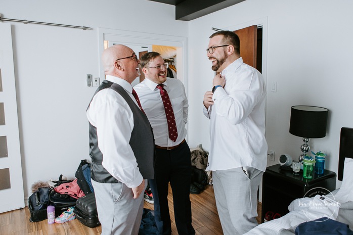 Groom getting ready with groomsmen in hotel room. Winter wedding photos. Mariage à Chicoutimi en hiver. Mariage Hôtel Chicoutimi. Photographe de mariage au Saguenay.