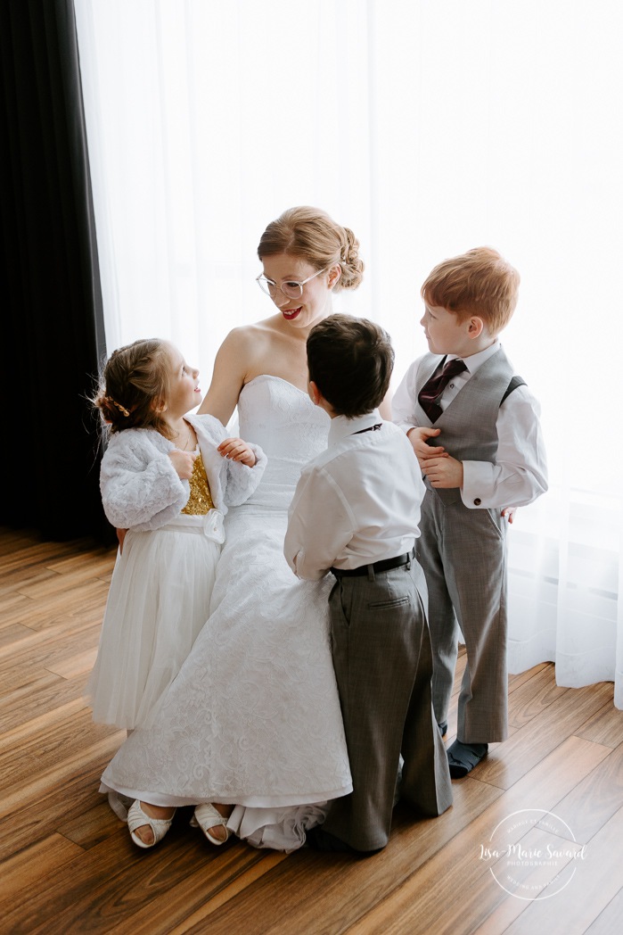 Bride hugging flower girl and ring boys. Winter wedding photos. Mariage à Chicoutimi en hiver. Mariage Hôtel Chicoutimi. Photographe de mariage au Saguenay.