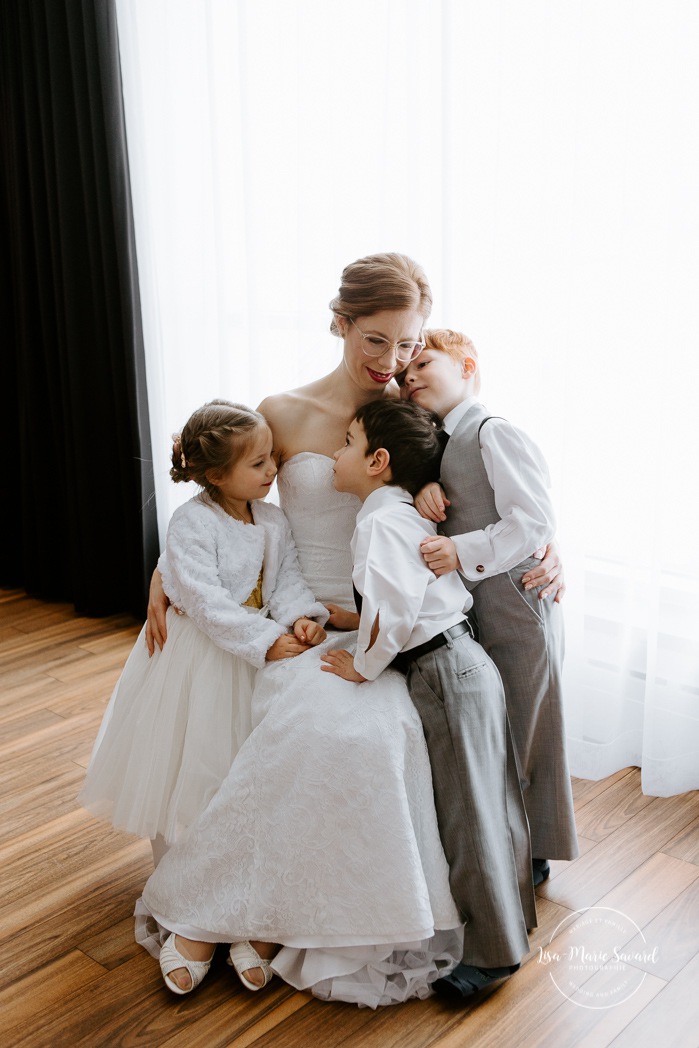 Bride hugging flower girl and ring boys. Winter wedding photos. Mariage à Chicoutimi en hiver. Mariage Hôtel Chicoutimi. Photographe de mariage au Saguenay.