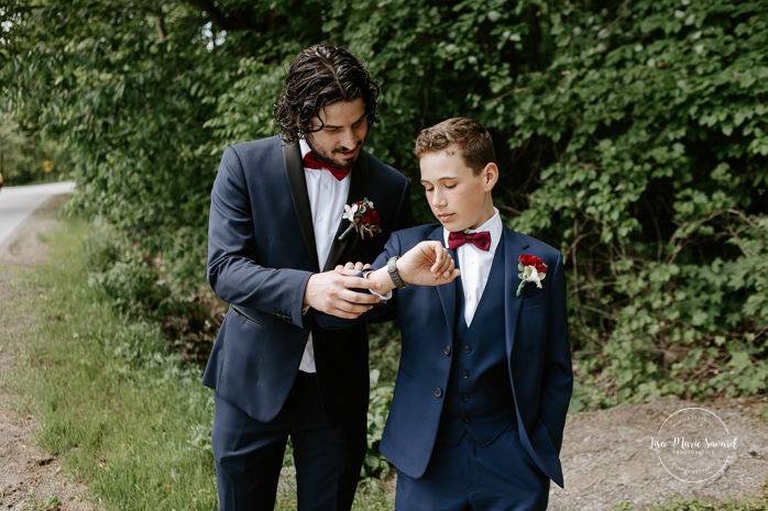 Groom and son looking at watch before ceremony. Mariage au Pavillon des Gallant. Auberge des Gallant wedding. Photographe mariage Montréal. Montreal wedding photographer.