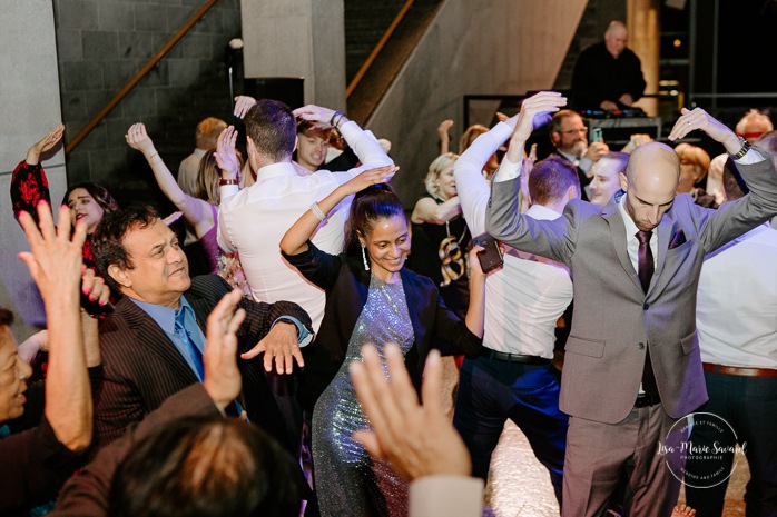 Wedding guests partying on the dancefloor. Wedding reception inside museum hall. Mariage au Musée de la Civilisation Québec Mariage dans le Vieux-Québec. Photographe mariage Québec. Old Quebec wedding photos.