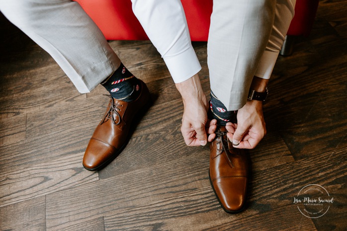 Groom putting shoes on. Groom getting ready with groomsmen in hotel room. Photographe de mariage en Mauricie. Mariage Le Baluchon Éco-Villégiature. 