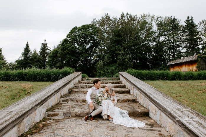 Romantic wedding photos. Bride and groom sitting on stone steps. Photographe de mariage en Mauricie. Mariage Le Baluchon Éco-Villégiature. 