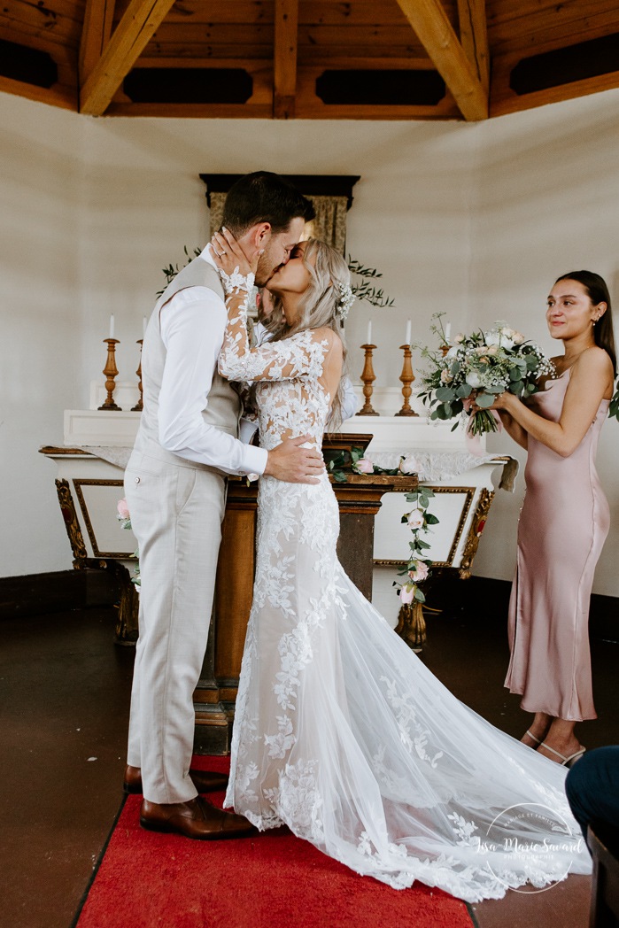 Bride and groom first kiss. Wedding ceremony in intimate chapel. Photographe de mariage en Mauricie. Mariage Le Baluchon Éco-Villégiature. 