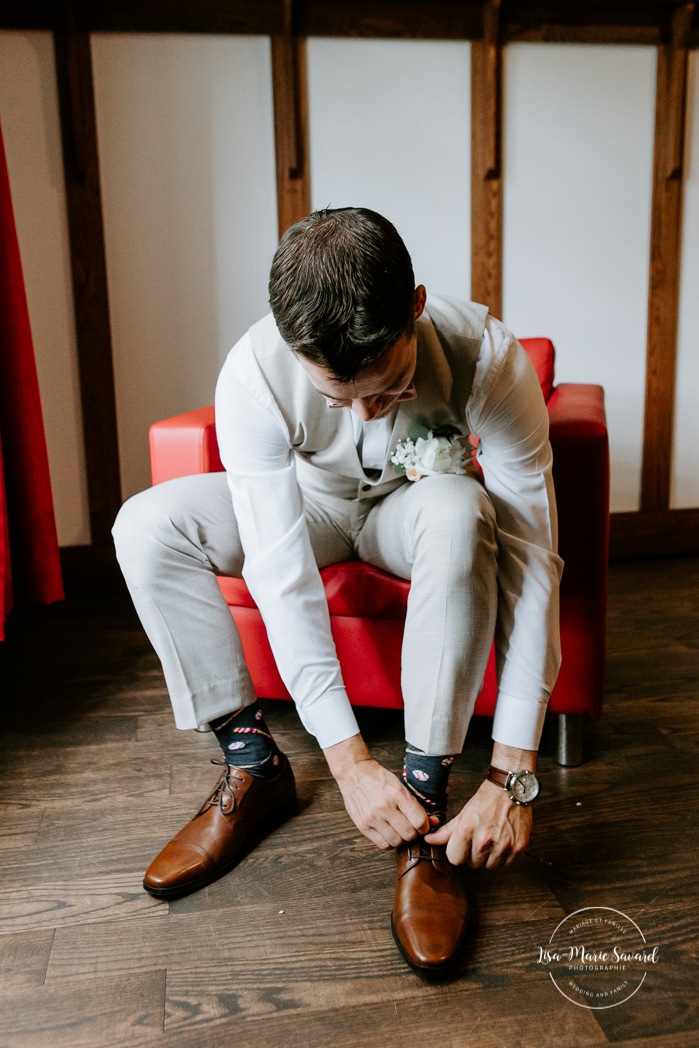 Groom putting shoes on. Groom getting ready with groomsmen in hotel room. Photographe de mariage en Mauricie. Mariage Le Baluchon Éco-Villégiature. 
