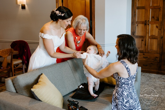 Bride getting ready with infant daughter and family in hotel room. Photographe de mariage à Mont-Tremblant. Mariage Le Grand Lodge Mont-Tremblant. Mont-Tremblant wedding photographer. Tremblant wedding photos.