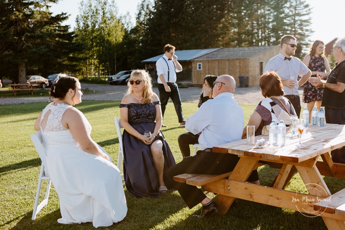Bride and groom enjoying cocktail with guests. Photographe de mariage au Lac-Saint-Jean. Photographe mariage Saguenay. Mariage à L'Orée des Champs Saint-Nazaire.