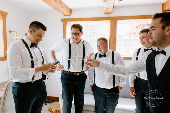 Groom offering flasks to groomsmen. Photographe de mariage au Lac-Saint-Jean. Photographe mariage Saguenay. Mariage à L'Orée des Champs Saint-Nazaire.