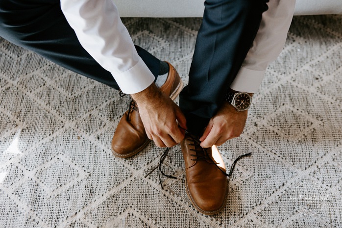 Groom putting shoes on. Photographe de mariage au Lac-Saint-Jean. Photographe mariage Saguenay. Mariage à L'Orée des Champs Saint-Nazaire.