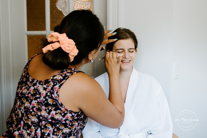 Bride getting ready with two bridesmaids and mother in hotel room. Photographe de mariage en Estrie. Photographe de mariage Cantons de l'Est. Mariage Estrimont Suites et Spa Orford.