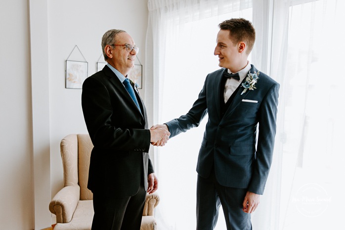 Groom's father helping groom put on bow tie. Photographe mariage au Verger du Flanc Nord. Verger du Flanc Nord wedding photographer. Photographe mariage Montérégie. Photographe mariage Montréal. Monteregie wedding photographer. Montreal wedding photographer.