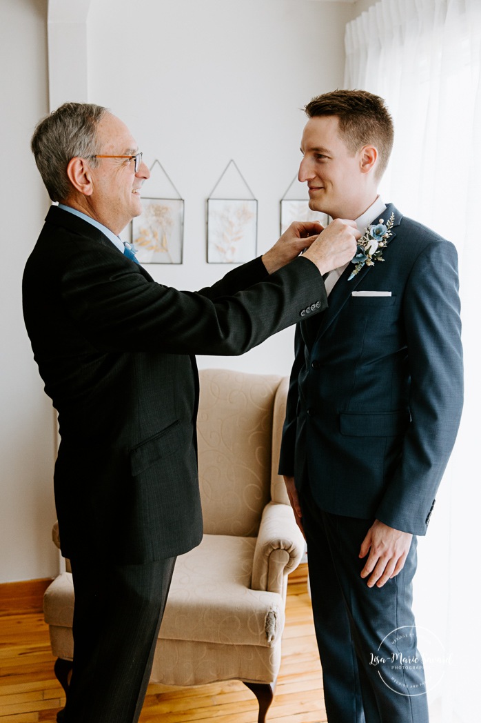 Groom's father helping groom put on bow tie. Photographe mariage au Verger du Flanc Nord. Verger du Flanc Nord wedding photographer. Photographe mariage Montérégie. Photographe mariage Montréal. Monteregie wedding photographer. Montreal wedding photographer.