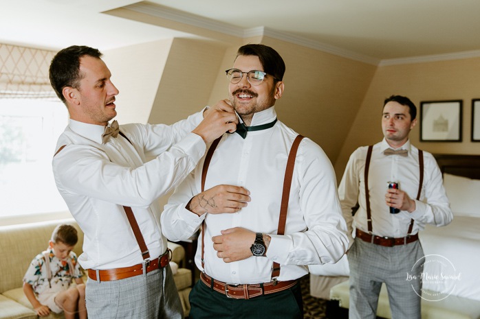 Groom getting ready with groomsmen in hotel room. Mariage au Manoir Richelieu à Charlevoix. Photographe de mariage à Charlevoix. Fairmont Le Manoir Richelieu.