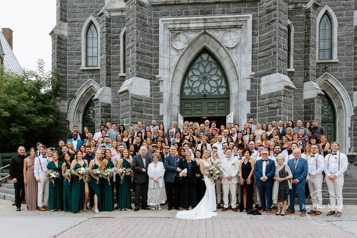 Large group photo in front of church. Mariage dans une église. Église du Sacré-Coeur Chicoutimi. Mariage à la Pulperie de Chicoutimi. Photographe de mariage au Saguenay-Lac-Saint-Jean. Photographe mariage Saguenay.