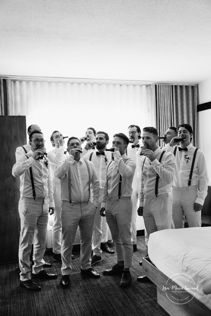 Groom getting ready with 10 groomsmen in a hotel room. Hotel Le Montagnais. Mariage à la Pulperie de Chicoutimi. Photographe de mariage au Saguenay-Lac-Saint-Jean. Photographe mariage Saguenay.